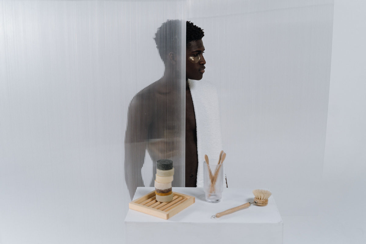 A person behind a screen with natural body care items, creating a minimalist and modern aesthetic.